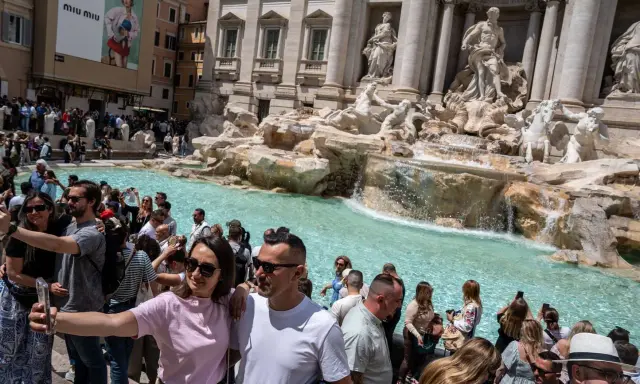 Foule de touristes admirant la fontaine de Trevi, la fontaine de l'amour à Rome, prenant des selfies devant les statues majestueuses et l'eau turquoise.
