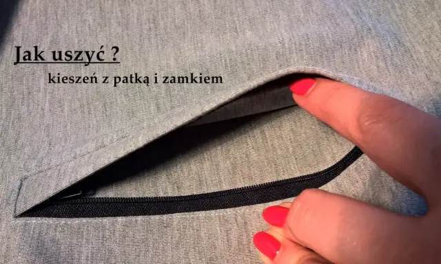 Szara tkanina z widocznym zamkiem i patką. Dłoń z czerwonym lakierem do paznokci wsuwa się do kieszeni z patką.