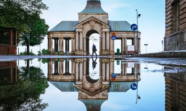 Odbicie zabytkowej budowli w kałuży, tworzące surrealistyczny widok. Nietypowe atrakcje Szczecin w deszczowy dzień.