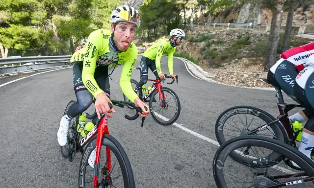 Jonas Rutsch zeigt Zunge auf dem Rennrad, während er auf einer kurvigen Bergstraße fährt.