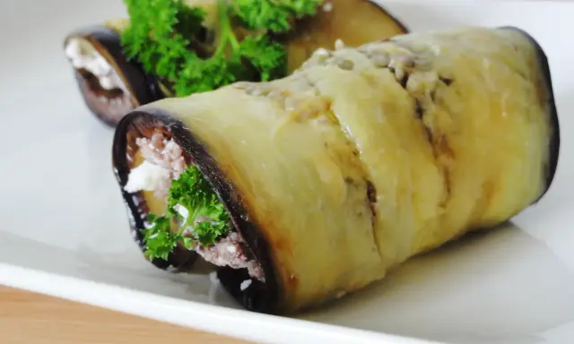 Rouleaux d'aubergine farcie au fromage et aux herbes, garniture appétissante.