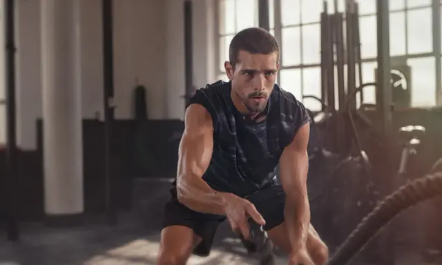 Ein Mann trainiert mit Seilen im Fitnessstudio. Das ist funktionelles Training, das Kraft und Ausdauer verbessert.