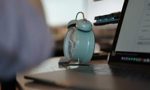 Budzik obok laptopa i klawiatury. Czas na pracę na 3/4 etatu.