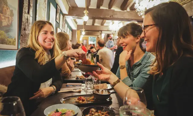 Amies joyeuses partageant des tapas dans un resto ouvert le dimanche à Rennes. Ambiance chaleureuse et conviviale.