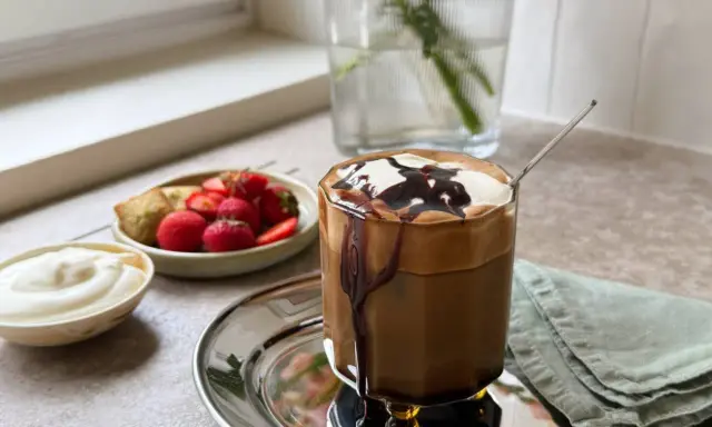 En läcker frappe med chokladsås och grädde, serverad med färska jordgubbar och en bit bakverk. Ett perfekt frappe recept för en solig dag.