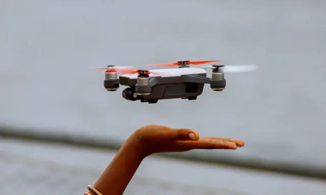 Kleine Drohne schwebt über einer Hand. Perfekt für den Einstieg, da sie die Drohne unter 250g Regeln erfüllt.