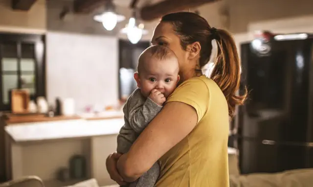 Zmęczona mama tuli dziecko, szukając sposobu, jak oduczyć dziecko jeść w nocy.