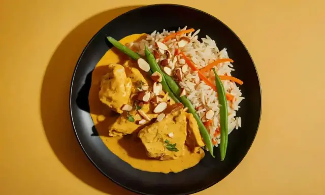 Aksamitny kurczak curry w kremowym sosie, podany z ryżem basmati, fasolką szparagową i płatkami migdałów.