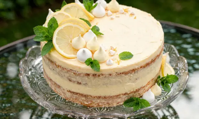 Cytrynowy tort z kremem lemon curd, udekorowany plasterkami cytryny, bezą i miętą.