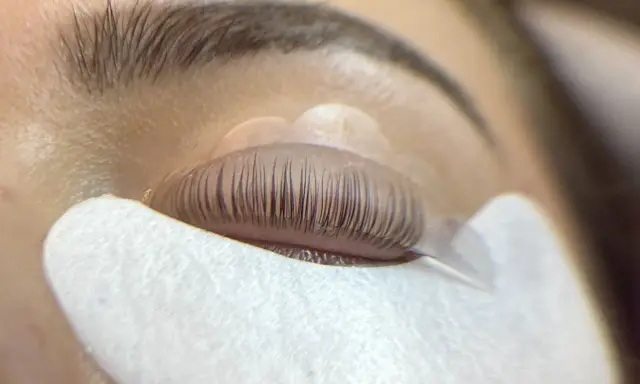 Un œil fermé, les cils recourbés sur un pad, prêts pour un allongement.