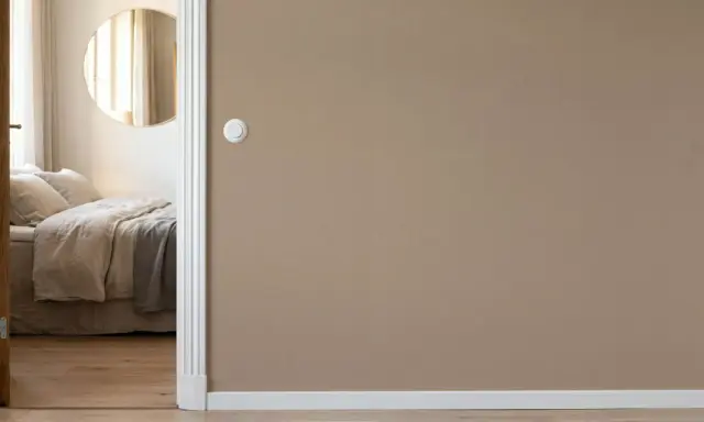Camera da letto con letto accogliente, specchio rotondo e pareti color taupe.