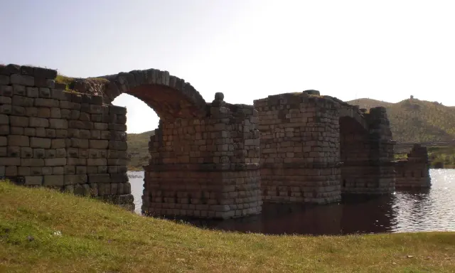 El imponente puente de Alconetar, con sus robustos arcos de piedra, se alza sobre las aguas, testigo de siglos de historia.