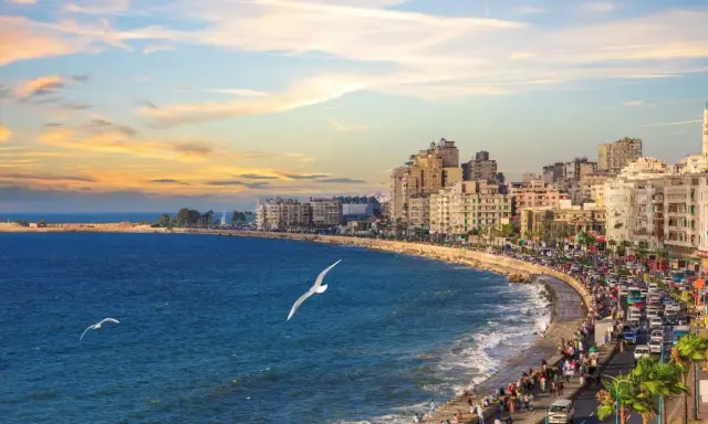 Il porto di Alessandria d'Egitto, con la sua vivace Corniche al tramonto, le onde del Mediterraneo e i gabbiani in volo.