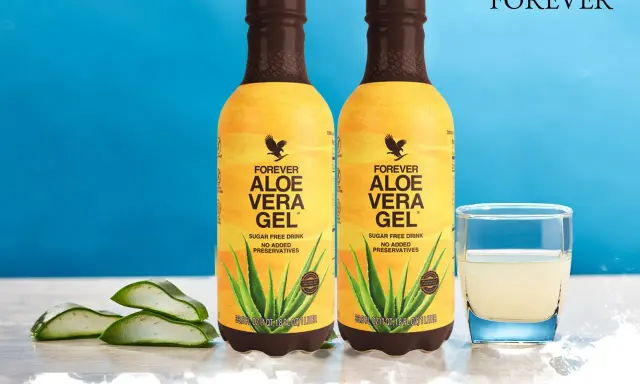 Dwa butelki napoju Forever Aloe Vera Gel, z widocznymi plastrami aloesu i szklanką napoju. Odkryj aloes właściwości.