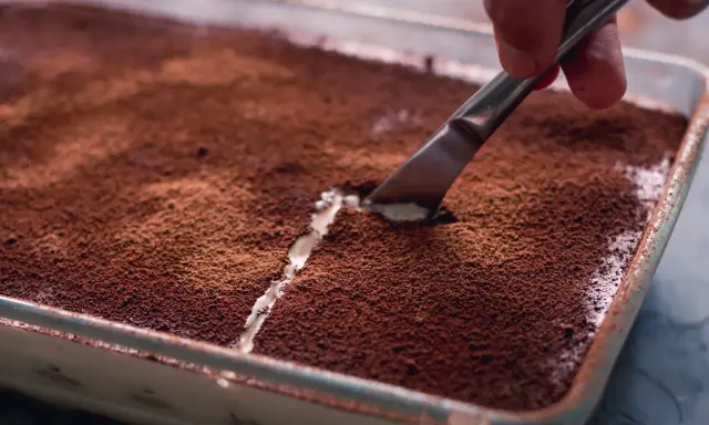 Kto pyta, czy mascarpone jest fit, gdy widzi tak kuszące tiramisu? Nóż kroi deser, odsłaniając kremową warstwę.