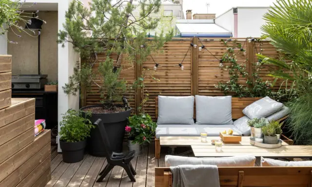 Aménagement terrasse avec pots : un coin salon cosy avec banquette, table basse, et verdure. Parfait pour se détendre.