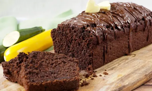 Saftiger schokokuchen mit zucchini, überzogen mit Schokoladenglasur und garniert mit zwei kleinen Herzchen aus hellem Teig.