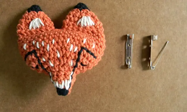 Un adorable zorro naranja tejido a crochet, listo para convertirse en un broche. ¡Perfecto para quienes buscan patrones de broches crochet únicos!