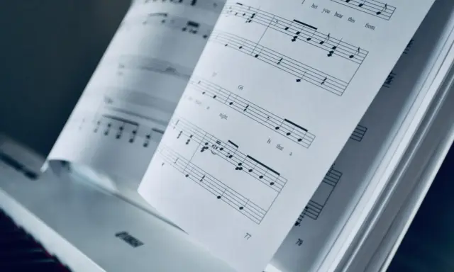 Partition piano triste ouverte sur un piano. Les notes semblent raconter une histoire mélancolique.