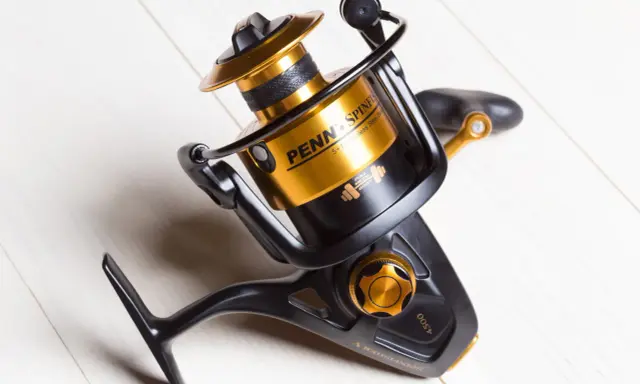 Czarny kołowrotek spinningowy Penn Spinfisher V 4500 ze złotymi akcentami, idealny do plecionki.