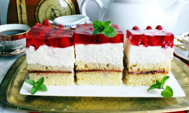 Pyszny biszkopt z serkiem mascarpone i bitą śmietaną, przełożony dżemem, z galaretką truskawkową i malinami.