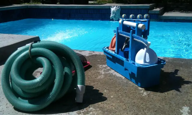 Un tuyau vert enroulé et une boîte bleue avec des accessoires de piscine, prêts pour le nettoyage. L'ordre des filtres à eau est essentiel pour une eau claire.