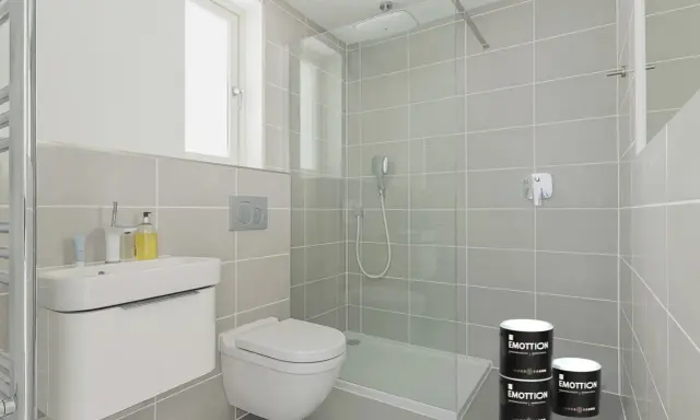 Dos latas de pintura "EMOTTION" listas para renovar el suelo del baño, con un diseño moderno y minimalista.