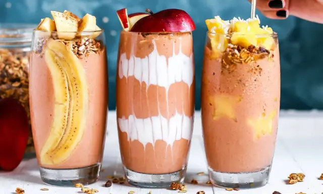 Drei leckere, bunte Smoothies im Glas, garniert mit Früchten und Müsli. Perfekt für den gesunden **Aufbau-Shake** am Morgen.