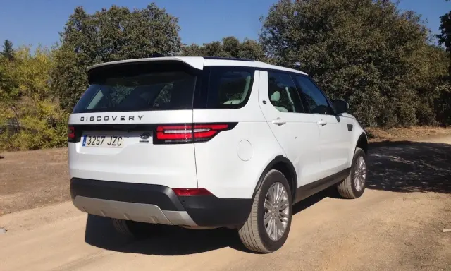 Un Land Rover Discovery HSE blanco aparcado en un camino de tierra rodeado de árboles.