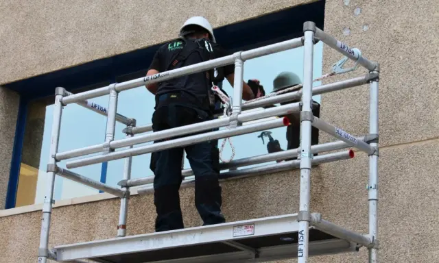 Técnico trabajando en un andamio, revisando las partes de un andamio para asegurar su estabilidad.
