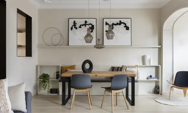 Comedor moderno con paredes color beige arena, mesa de madera, sillas grises y arte abstracto.