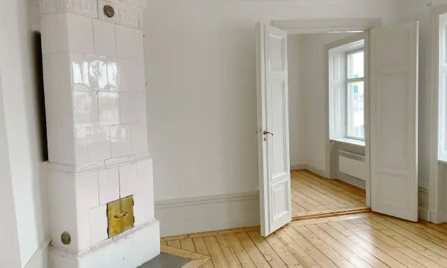 Vitt, vackert kakelugn med mässingsluckor. Tänk att elda i kakelugn en kall vinterdag.