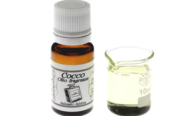 Flacone di olio di cocco fragranza, ideale per balsamo labbra, accanto a un bicchierino graduato con il liquido.