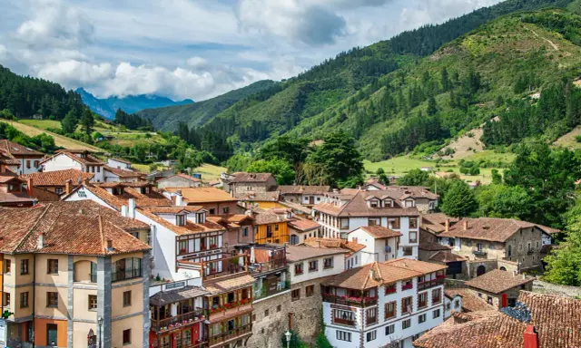Potes, un pintoresco pueblo en los Picos de Europa, con casas de tejados rojos y montañas verdes de fondo.