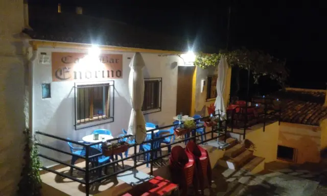 Bar Endrino, un lugar acogedor donde comer en Segura de la Sierra. Mesas y sillas azules y rojas esperan bajo luces cálidas.