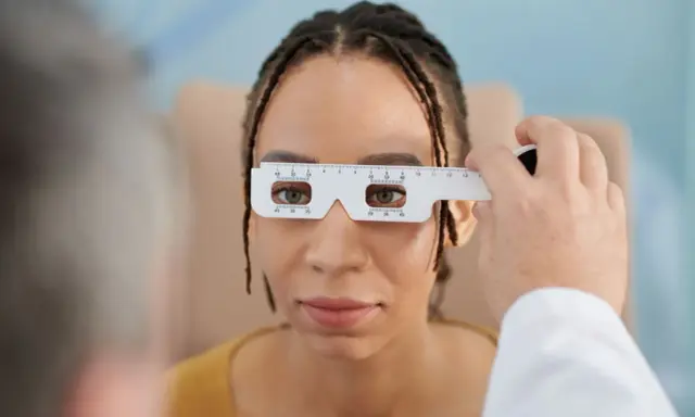 Badanie wzroku u optometrysty. Pacjentka ma na nosie przyrząd do pomiaru rozstawu źrenic. Czas oczekiwania na okulary zależy od wielu czynników.