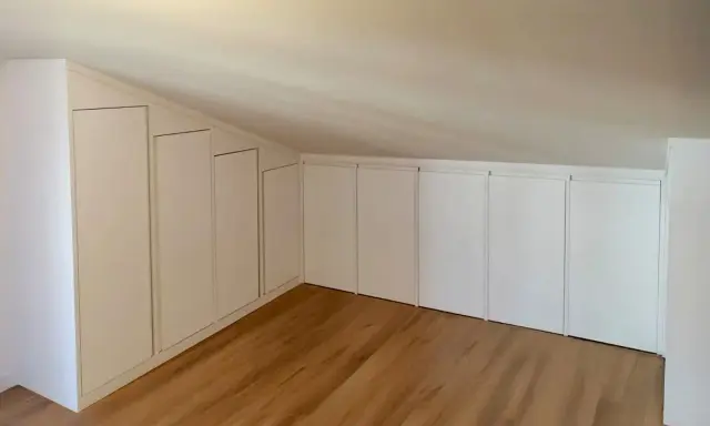 Armadi su misura sfruttano ogni centimetro, perfette idee sottotetto molto basso. Pavimento in legno chiaro.