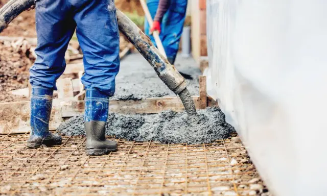 Pracownicy wylewają beton na zbrojenie. Sprawdzamy, jaka jest suchy beton cena 1m3.
