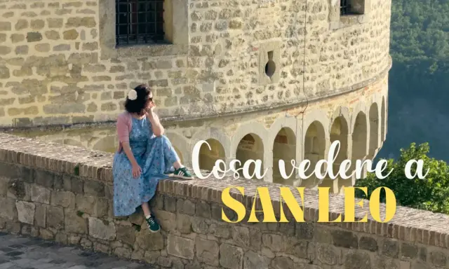 Donna seduta su un muretto di pietra, con vista panoramica. Un'ottima pausa durante il trekking a San Leo.