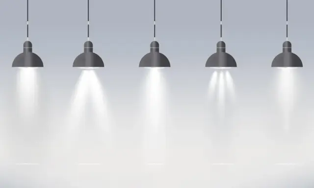 Pięć wiszących lamp tworzy oświetlenie miejscowe, rzucając snopy światła na pustą przestrzeń.