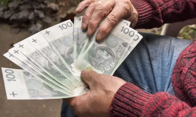 Dłoń trzyma wachlarz banknotów 100 zł. Czy to uczciwy zarobek, czy szalbierstwo?
