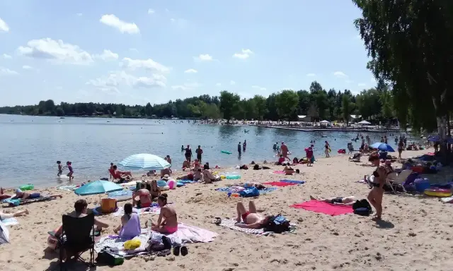 Słoneczny dzień nad zalewem Sosina. Ludzie odpoczywają na plaży, kąpią się i opalają.