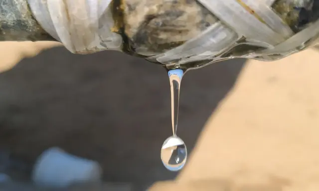 Gota de agua cayendo de una tubería rota, indicando la necesidad de reparar tubería.