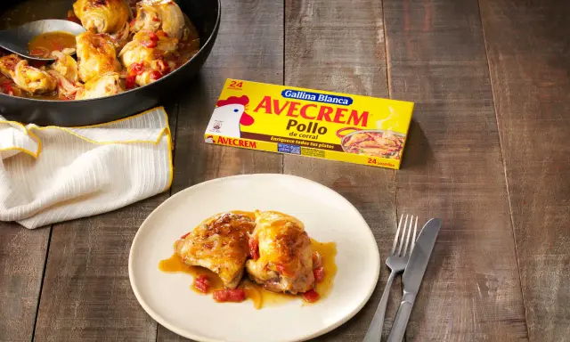 Sabroso pollo con sopa de cebolla y cerveza, servido en sartén y plato. Caja de Avecrem Pollo al lado.