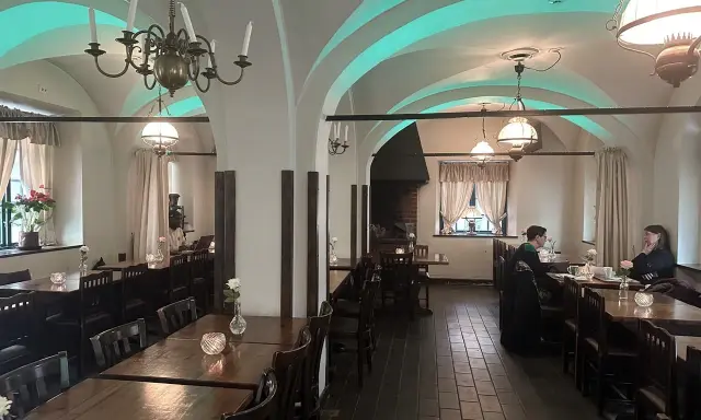 Mysig interiör på Cafe Kronhuset med välvda tak och varma ljus. Två personer sitter vid ett bord och samtalar.