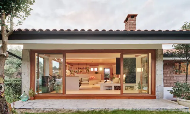 Ristrutturazione esterna di una casa anni '70: un'oasi moderna con ampie vetrate che si aprono sul verde.