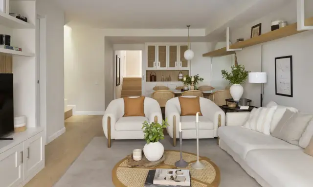 Salón rectangular dos ambientes con sofás blancos, sillones de borrego y mesa de centro de ratán.