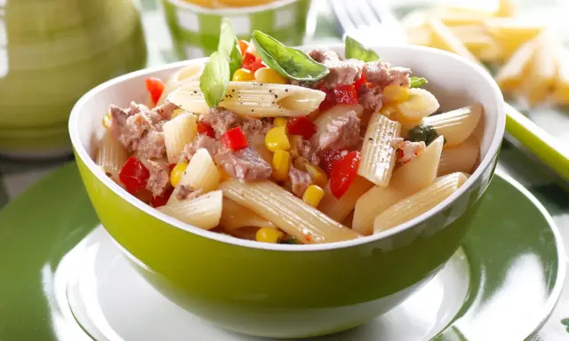Ein leckerer nudelsalat mit thunfisch, Mais und Paprika, garniert mit Basilikum.