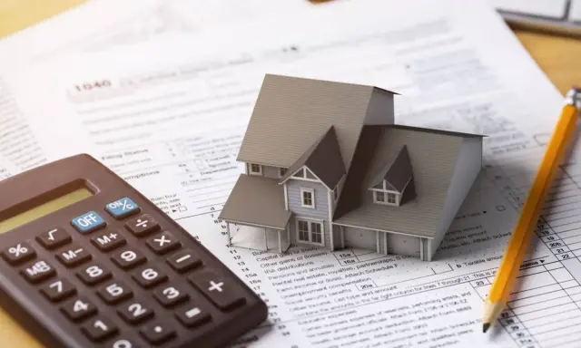 Casa modelo sobre formulario 1040, calculadora y lápiz. El arte 3 lau se relaciona con la planificación fiscal.