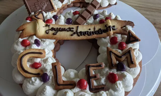 Gâteau d'anniversaire en forme de chiffres, décoré de crème fouettée, de biscuits lettres formant "CLEM", de chocolats et de bonbons. Quelle crème pour recouvrir un gâteau ? Celle-ci est parfaite !